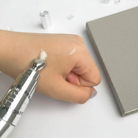 Hand applying cream to skin with a silver applicator
